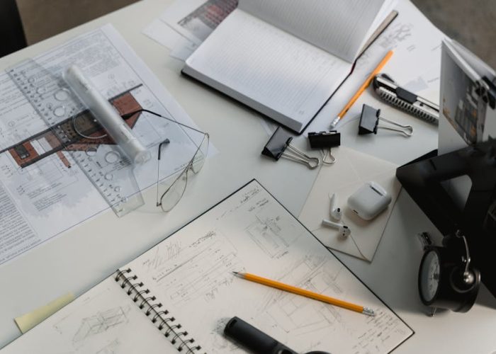 A busy architectural workspace featuring blueprints, sketches, and drafting tools.